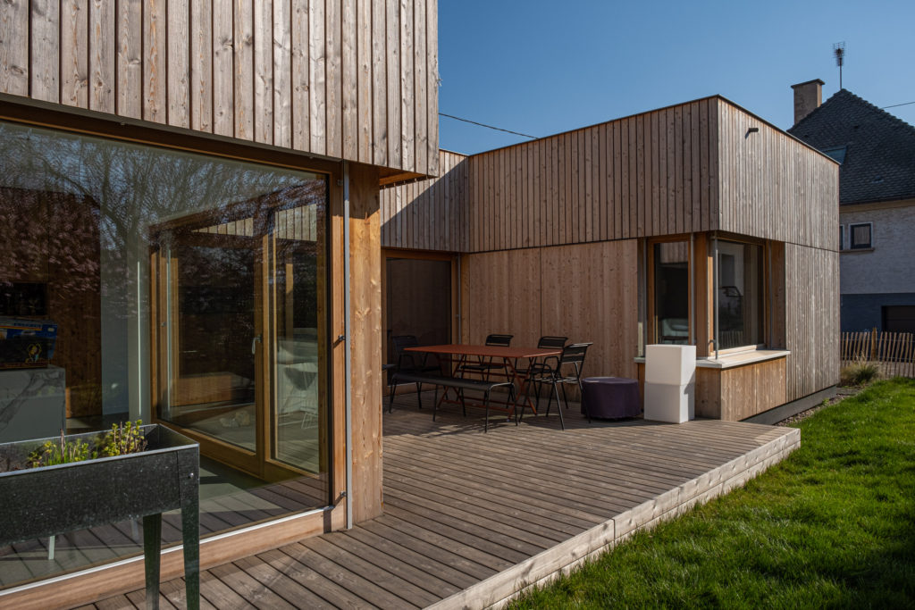 Vue extérieure de la façade d'une maison contemporaine ossature bois avec terrasse patio