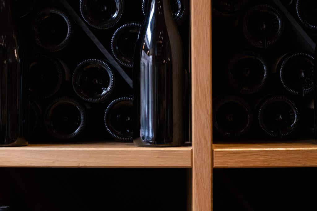 Détail d'un casier à vin au sein duquel sont rangées des bouteilles de vins