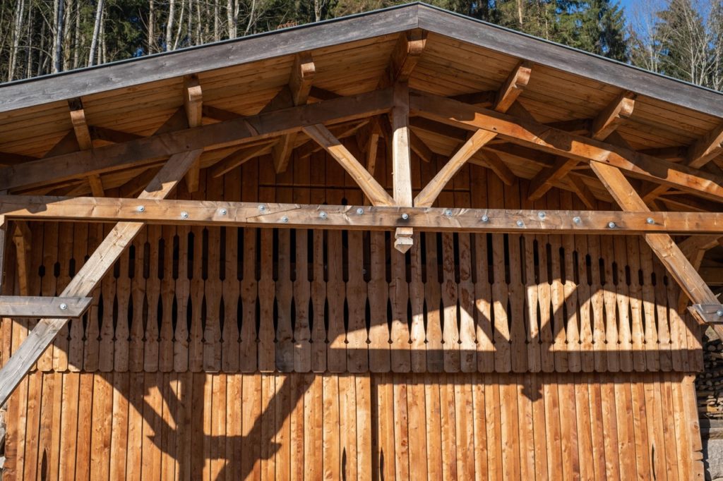 Hangar avec bardage chantourné en mélèze, charpente traditionnelle appararente en douglas