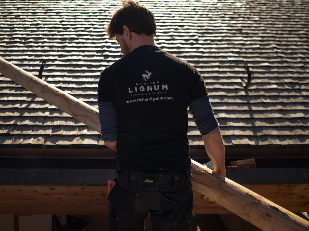 Jospeh Barotte vue de dos et portant un tee-shirt avec le logo de l'Atelier Lignum, ébénisterie et charpente 